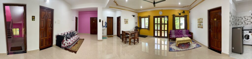 Panoramic view of a spacious living room at Happy Moon Homestay in Goa, featuring comfortable seating, vibrant decor, and a relaxing ambiance for families and groups.